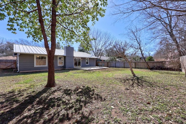 back of property featuring metal roof, a chimney, a patio, and a fenced backyard