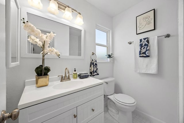 bathroom with toilet, baseboards, and vanity