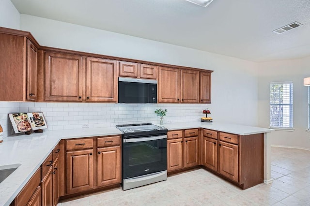 kitchen featuring black microwave, a peninsula, visible vents, brown cabinets, and stainless steel electric range oven