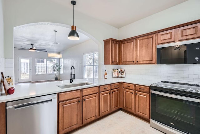 kitchen featuring a peninsula, appliances with stainless steel finishes, brown cabinets, and a sink