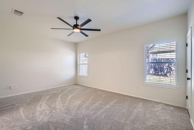 carpeted empty room featuring a ceiling fan, visible vents, and baseboards