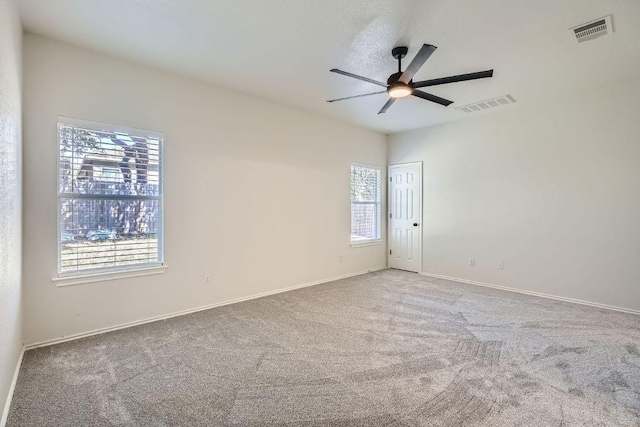 carpeted empty room with ceiling fan, visible vents, and baseboards