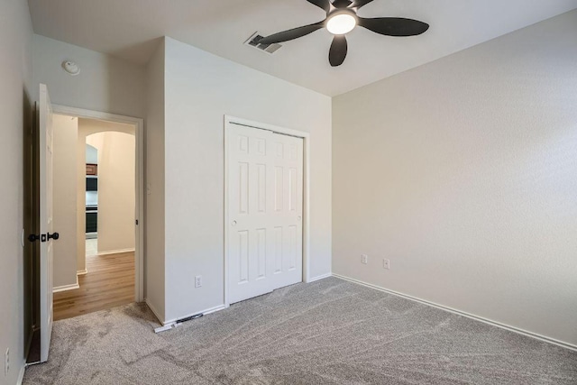 unfurnished bedroom with arched walkways, a closet, visible vents, and carpet flooring