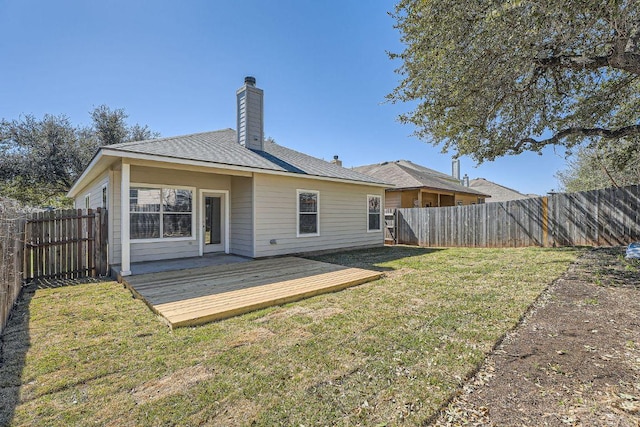 rear view of house with a deck, a fenced backyard, a lawn, and a chimney