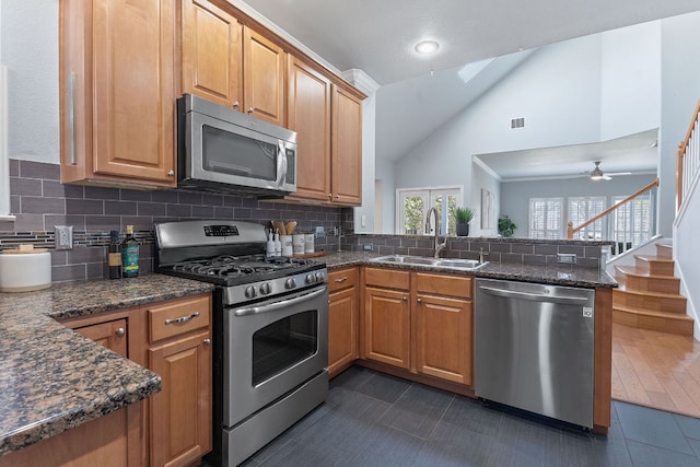 kitchen featuring vaulted ceiling with skylight, tasteful backsplash, appliances with stainless steel finishes, a peninsula, and a sink