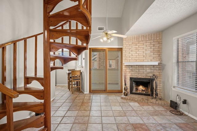 interior space with a fireplace, visible vents, a ceiling fan, a textured ceiling, and baseboards