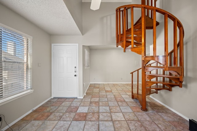 entrance foyer with stone finish floor, stairs, baseboards, and a textured ceiling