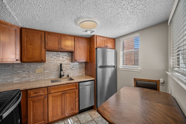 kitchen with appliances with stainless steel finishes, brown cabinets, and a sink