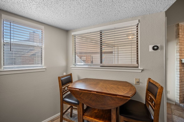 dining area with baseboards, a textured ceiling, and a textured wall