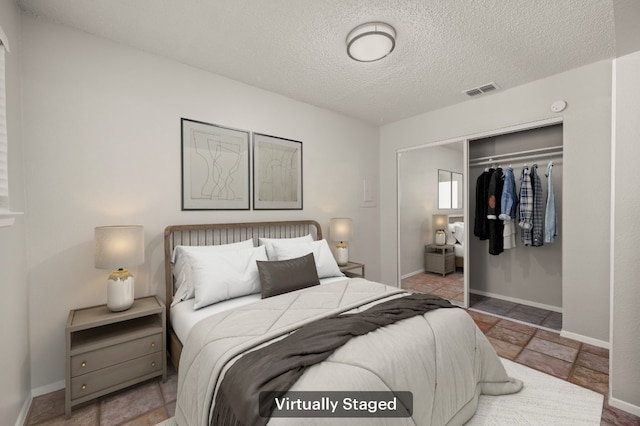 bedroom with baseboards, a textured ceiling, visible vents, and a closet