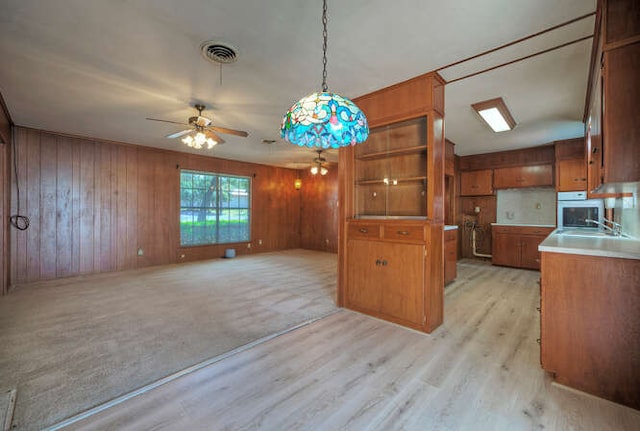 5600 Lakeview Dr, Austin, TX 78734 - kitchen featuring brown cabinetry, light wood-type flooring, pendant lighting, ceiling fan, and wooden walls