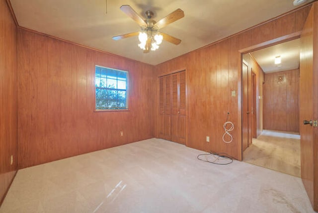 carpeted empty room with wood walls and a ceiling fan