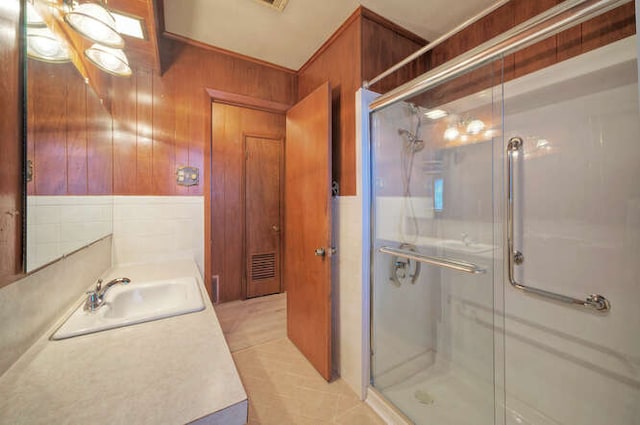 bathroom featuring wood walls, a shower stall, tile patterned floors, and vanity