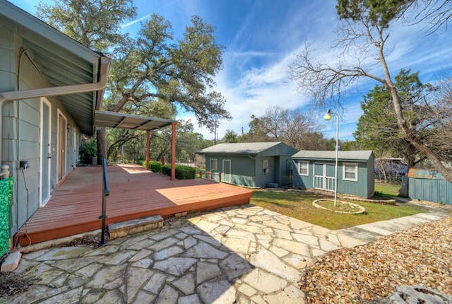 wooden deck featuring a yard, a patio, and an outdoor structure