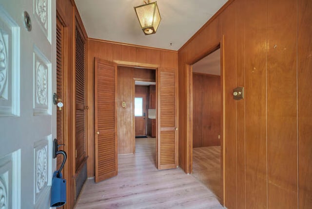 corridor with light wood-style floors and wooden walls