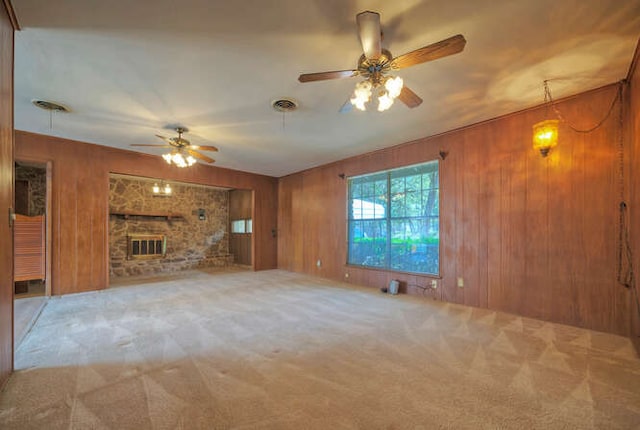 unfurnished living room featuring a brick fireplace, carpet flooring, wood walls, and visible vents