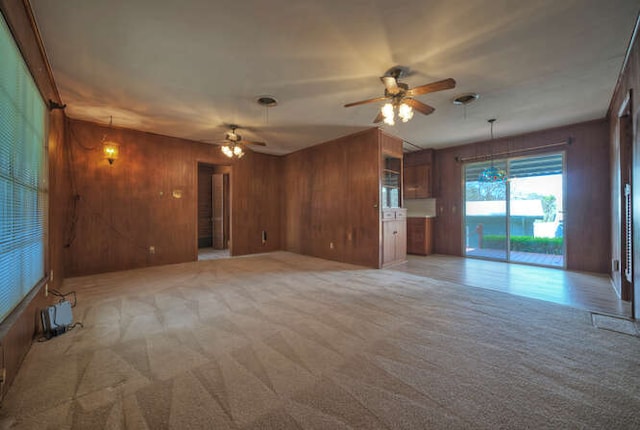 unfurnished living room featuring light colored carpet, ceiling fan, and wooden walls