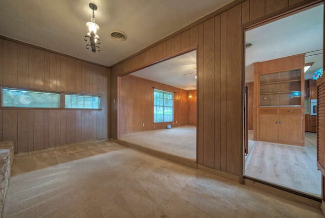 5600 Lakeview Dr, Austin, TX 78734 - carpeted empty room featuring wood walls, an inviting chandelier, and visible vents