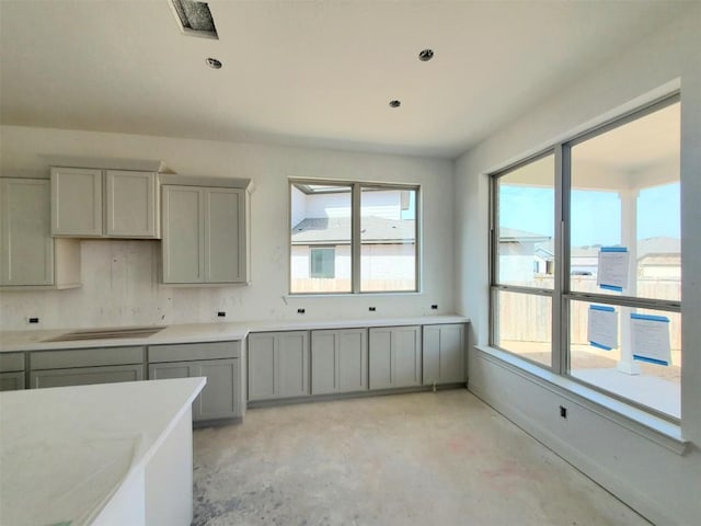 kitchen with concrete flooring, light countertops, gray cabinets, and baseboards