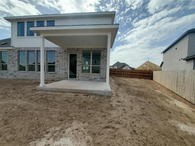 back of house with brick siding, a patio area, and a fenced backyard