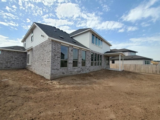 back of house featuring brick siding and fence