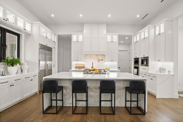 kitchen with white cabinetry, a kitchen island with sink, appliances with stainless steel finishes, and dark wood-style flooring