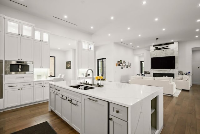 kitchen with white cabinetry, a kitchen island with sink, stainless steel oven, and a sink