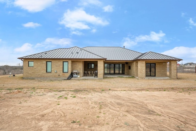 view of front of home with a standing seam roof, stone siding, and metal roof