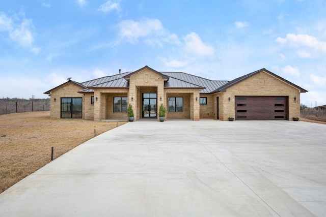 view of front facade featuring a garage, a standing seam roof, and metal roof