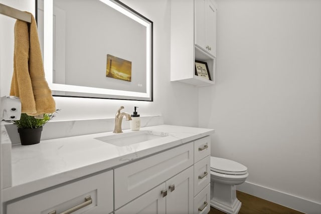 bathroom with baseboards, vanity, toilet, and wood finished floors