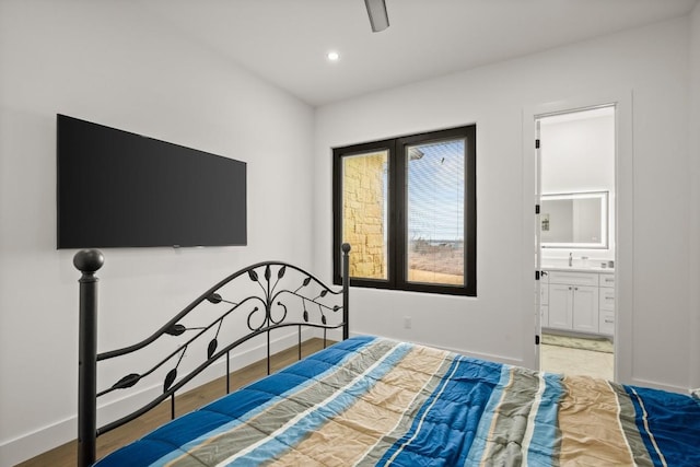 bedroom featuring recessed lighting, a sink, light wood-style floors, baseboards, and ensuite bath