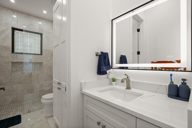 bathroom featuring recessed lighting, toilet, vanity, tile patterned flooring, and tiled shower