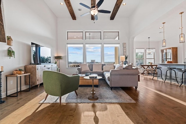 living room with visible vents, beamed ceiling, hardwood / wood-style floors, and ceiling fan with notable chandelier