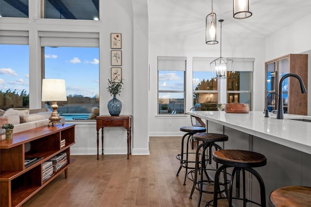 kitchen featuring a sink, wood finished floors, baseboards, a kitchen bar, and pendant lighting