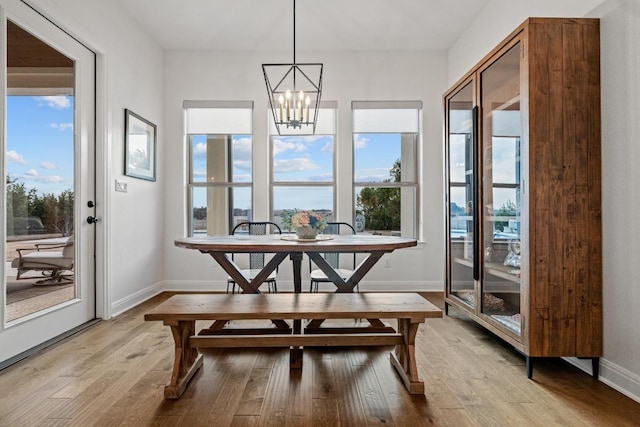 dining area featuring light wood-style floors, baseboards, and an inviting chandelier