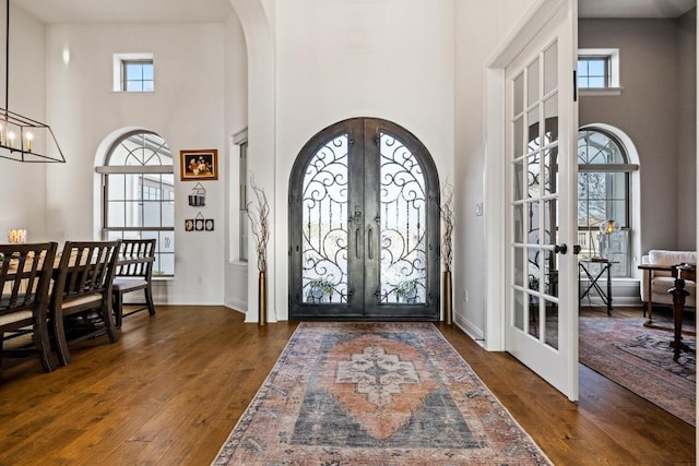 entryway featuring arched walkways, french doors, plenty of natural light, and wood finished floors