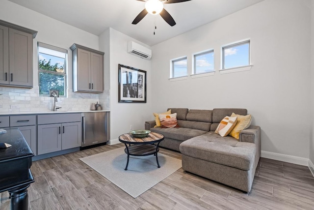 living room with a wall unit AC, ceiling fan, baseboards, and a wealth of natural light