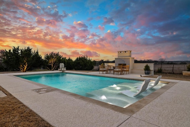 pool with exterior fireplace, a patio area, and fence