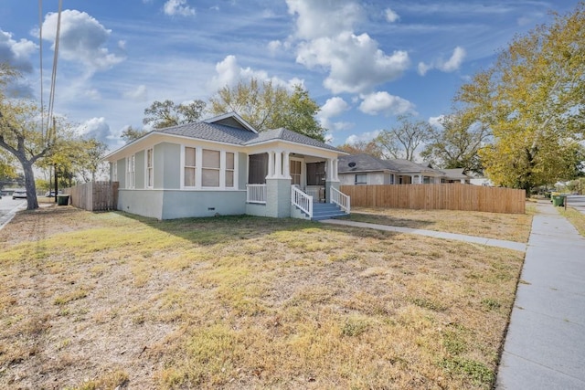 bungalow featuring covered porch, a front yard, fence, and stucco siding