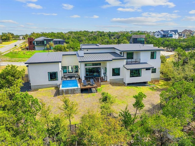 back of house featuring metal roof, a standing seam roof, fence, a yard, and stucco siding