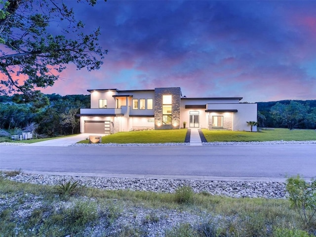 contemporary home with driveway, a yard, and stucco siding