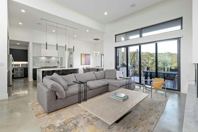 living room with concrete flooring, a towering ceiling, and recessed lighting