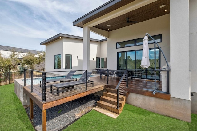 back of house with a fenced in pool, stucco siding, ceiling fan, fence, and a deck