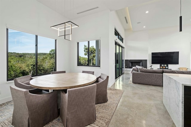 dining room with finished concrete flooring, recessed lighting, visible vents, a high ceiling, and baseboards