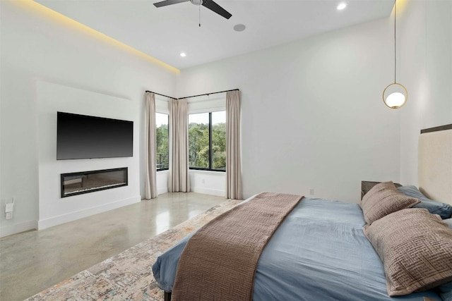 bedroom with concrete flooring, recessed lighting, a glass covered fireplace, and baseboards