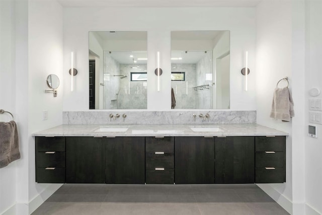 bathroom with double vanity, a stall shower, baseboards, and a sink