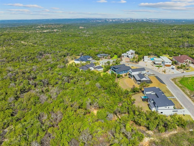 drone / aerial view featuring a wooded view and a residential view