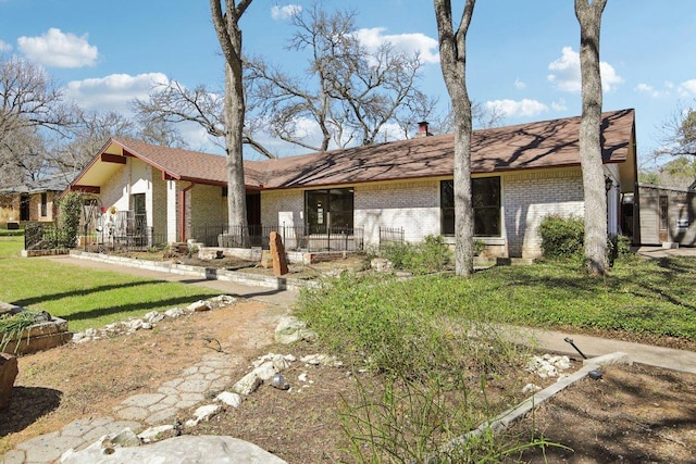 rear view of house featuring a yard and brick siding