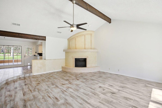 unfurnished living room featuring vaulted ceiling with beams, visible vents, a textured ceiling, wood finished floors, and a tile fireplace