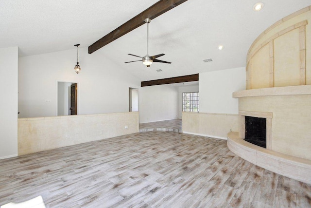 unfurnished living room with vaulted ceiling with beams, a large fireplace, ceiling fan, and wood finished floors